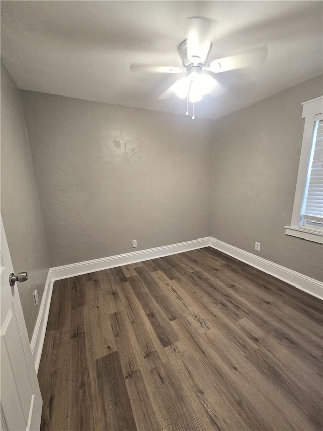 empty room with dark wood-style floors, baseboards, and a ceiling fan