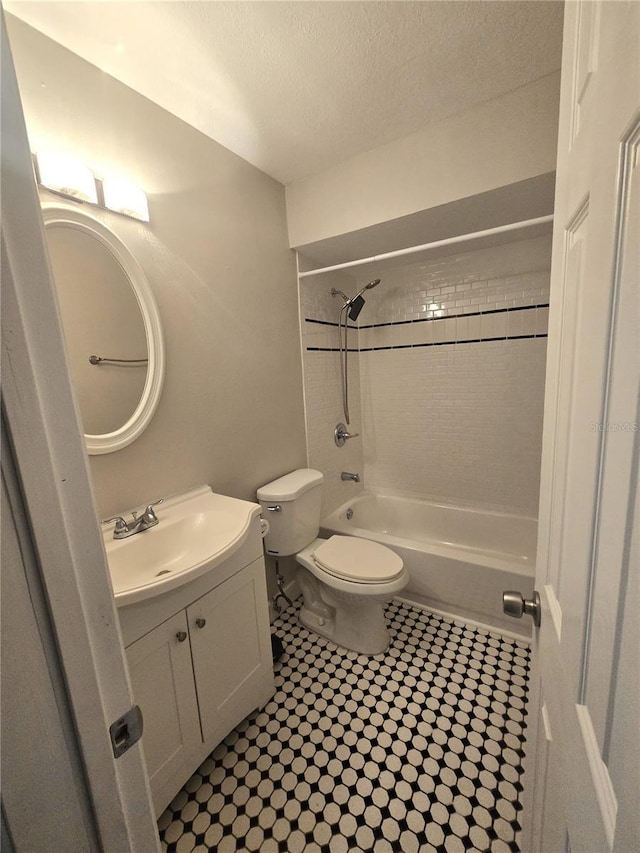 full bath featuring washtub / shower combination, a textured ceiling, toilet, and vanity