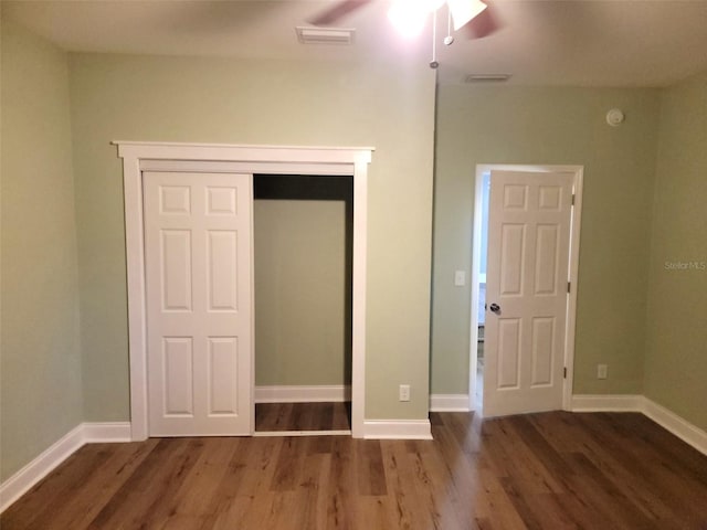 unfurnished bedroom with a closet, baseboards, and dark wood-type flooring