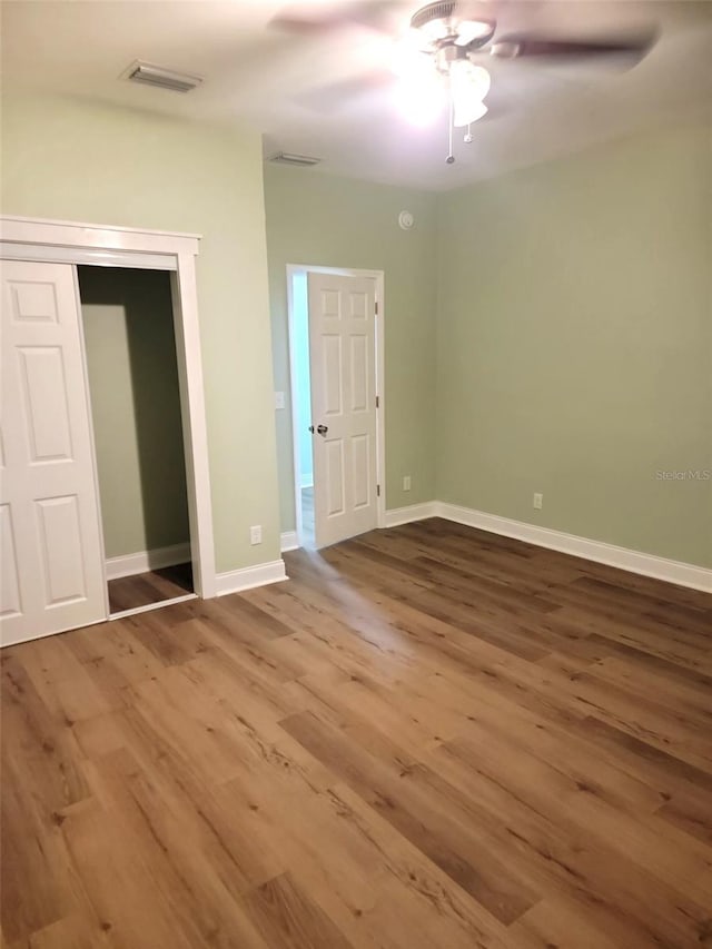 unfurnished bedroom with baseboards, a closet, visible vents, and wood finished floors