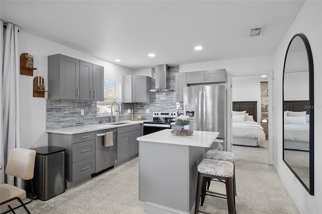 kitchen with appliances with stainless steel finishes, a center island, gray cabinets, and wall chimney exhaust hood