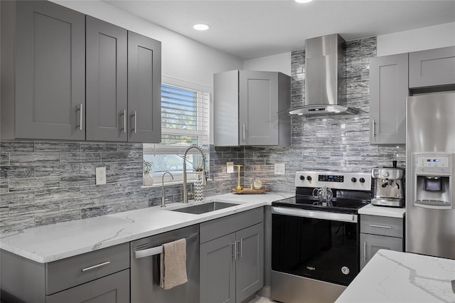 kitchen with gray cabinetry, sink, wall chimney range hood, and appliances with stainless steel finishes