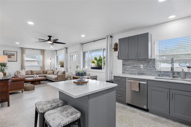 kitchen featuring stainless steel dishwasher, gray cabinets, sink, and a breakfast bar area