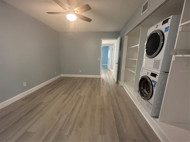 laundry area with stacked washer / drying machine, ceiling fan, and hardwood / wood-style flooring