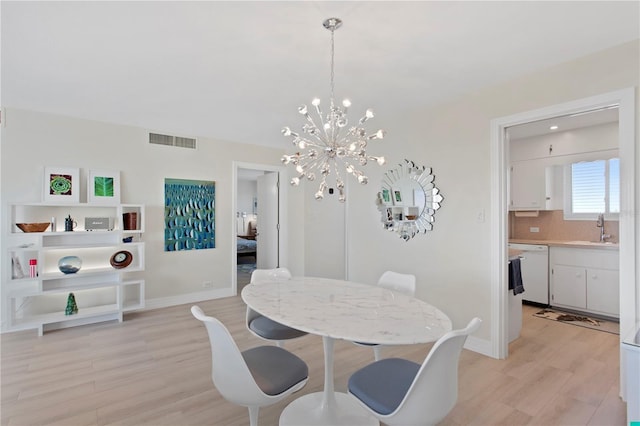 dining space featuring a notable chandelier, light wood-type flooring, and sink