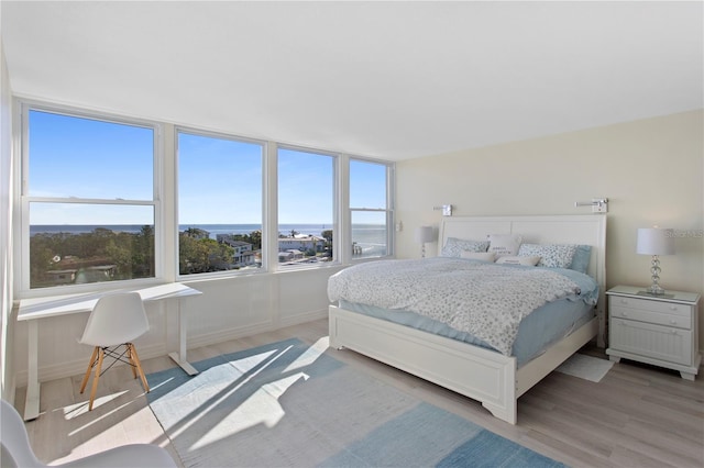 bedroom with a water view and light hardwood / wood-style flooring