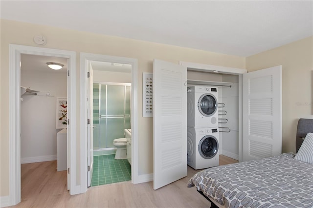 bedroom with ensuite bathroom, a closet, stacked washer and dryer, and light hardwood / wood-style flooring