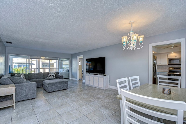 living room featuring ceiling fan with notable chandelier and a textured ceiling