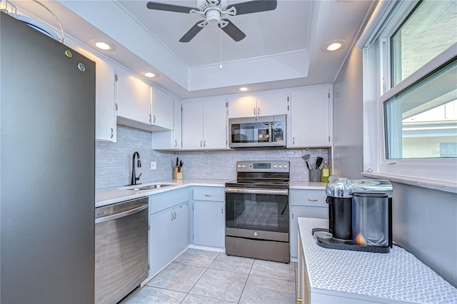 kitchen featuring appliances with stainless steel finishes, backsplash, a raised ceiling, ceiling fan, and sink