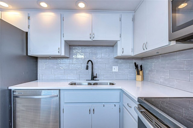 kitchen featuring backsplash, white cabinetry, sink, and appliances with stainless steel finishes