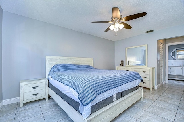 bedroom with a textured ceiling, ceiling fan, and connected bathroom