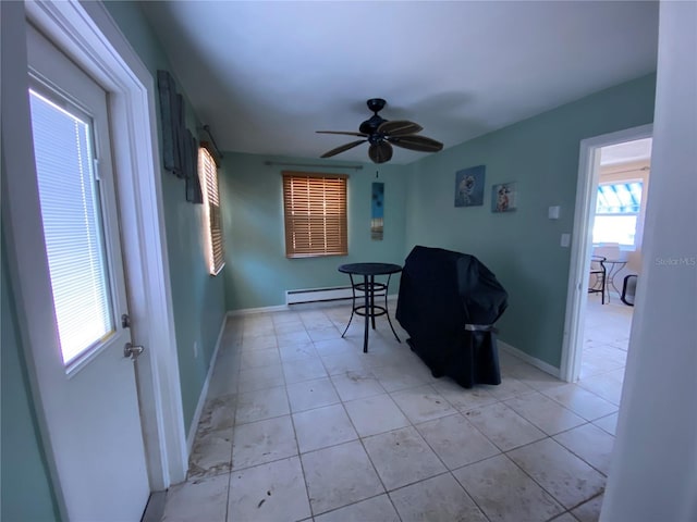 unfurnished room featuring ceiling fan, light tile patterned flooring, and baseboard heating