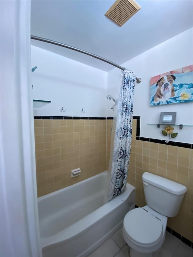 bathroom featuring tile patterned floors, shower / bath combination with curtain, tile walls, and toilet