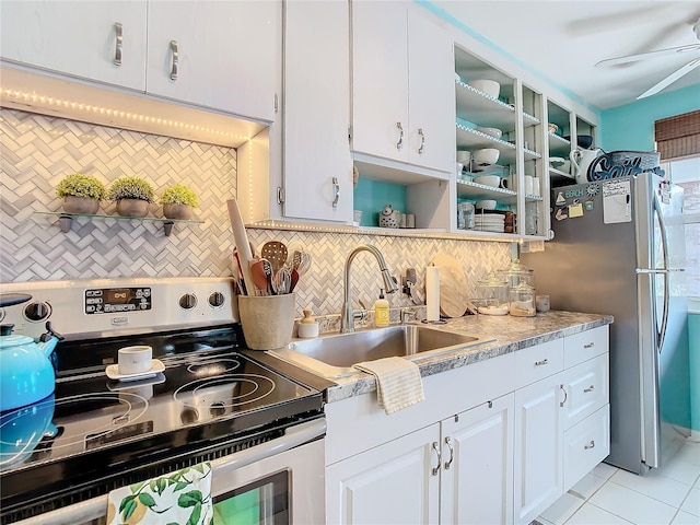 kitchen with appliances with stainless steel finishes, backsplash, sink, white cabinets, and light tile patterned flooring