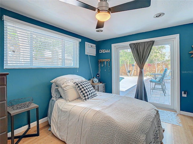 bedroom featuring ceiling fan, access to exterior, light wood-type flooring, and an AC wall unit