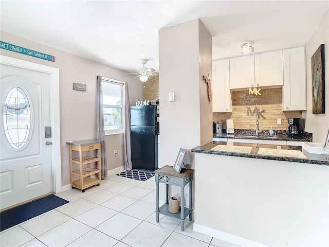 kitchen with decorative backsplash, black refrigerator, ceiling fan, sink, and white cabinets