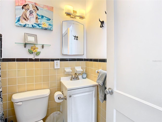 bathroom featuring vanity, tile walls, and toilet