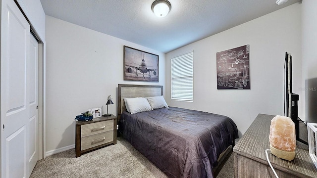 bedroom with a textured ceiling, light colored carpet, and a closet