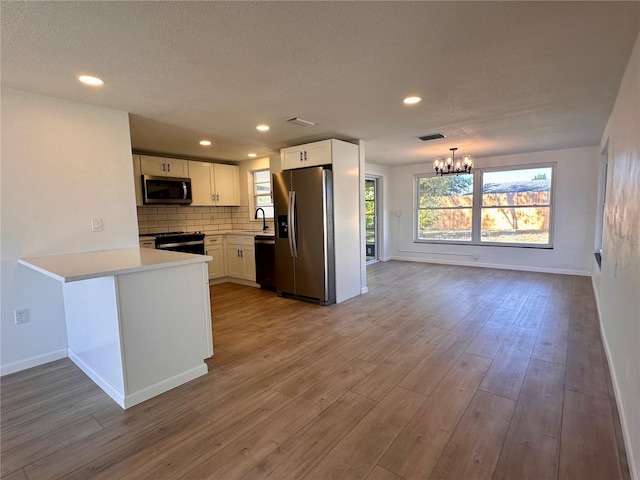 kitchen with white cabinetry, tasteful backsplash, a notable chandelier, kitchen peninsula, and black appliances