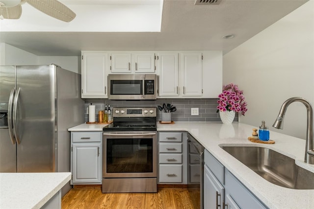 kitchen featuring appliances with stainless steel finishes, tasteful backsplash, ceiling fan, sink, and white cabinetry