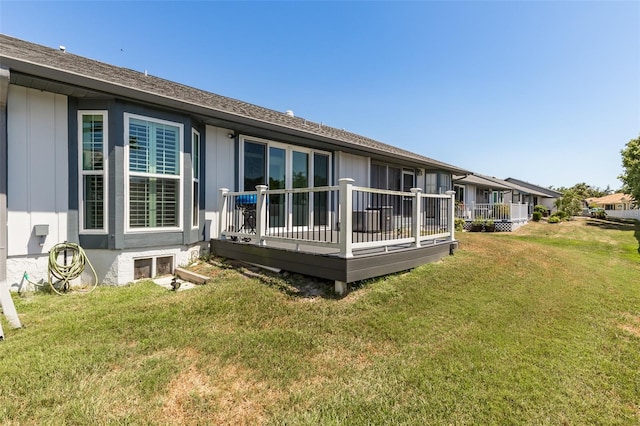 back of property featuring a deck and a lawn