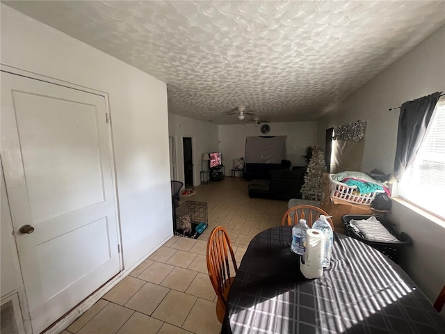 unfurnished dining area featuring ceiling fan, light tile patterned flooring, and a textured ceiling