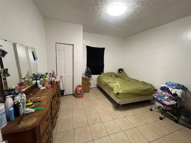 bedroom with light tile patterned floors, a textured ceiling, and a closet