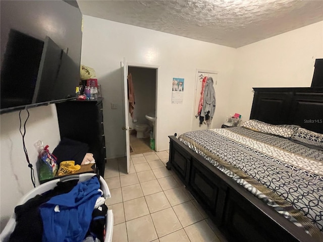 bedroom featuring light tile patterned floors, a textured ceiling, and ensuite bathroom