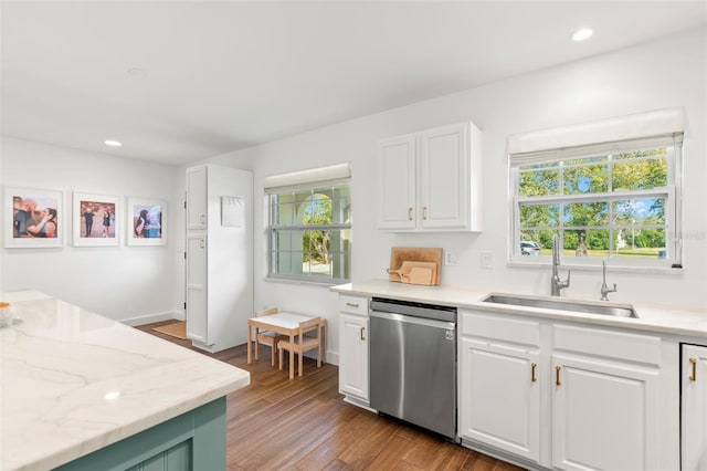 kitchen featuring stainless steel dishwasher, white cabinets, sink, and hardwood / wood-style flooring