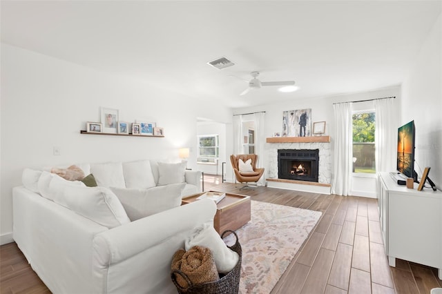 living room with ceiling fan and a stone fireplace