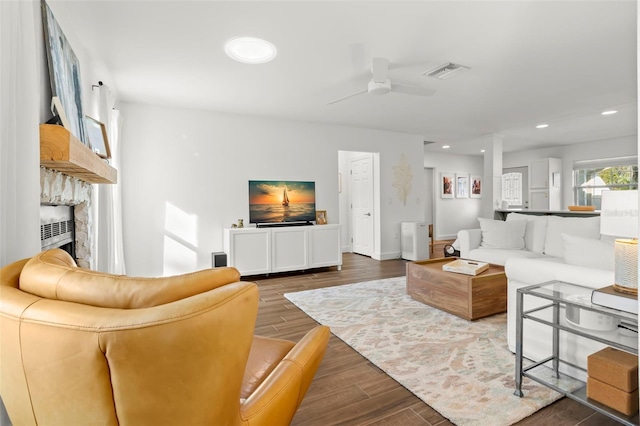 living room with a stone fireplace and ceiling fan