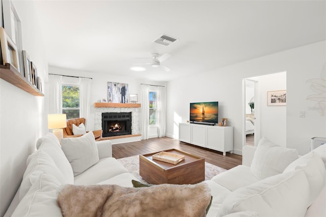 living room featuring a stone fireplace, ceiling fan, and hardwood / wood-style flooring