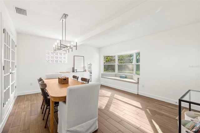 dining space featuring beamed ceiling, wood-type flooring, and a notable chandelier