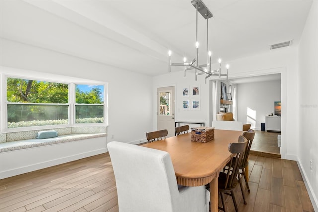 dining area with hardwood / wood-style floors and an inviting chandelier