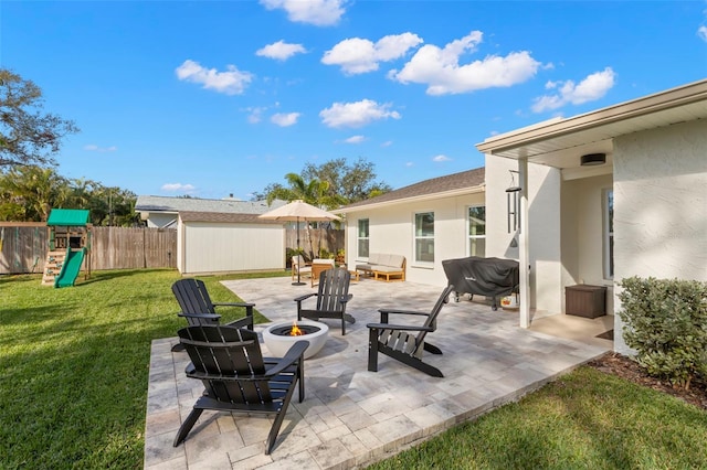 view of patio with a playground and an outdoor living space with a fire pit