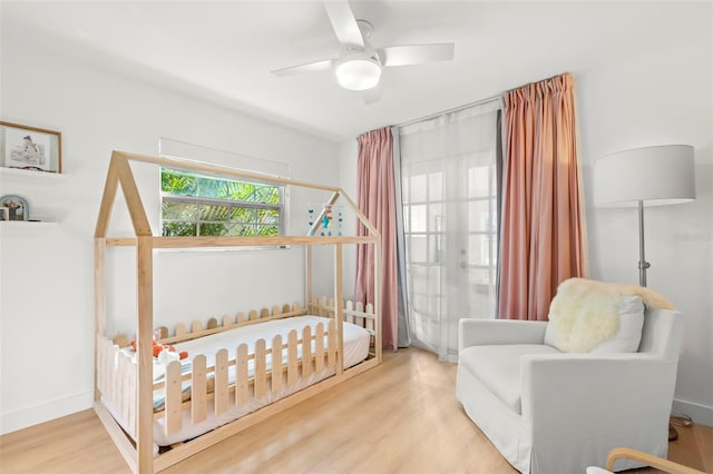 bedroom with ceiling fan, light hardwood / wood-style flooring, and a crib