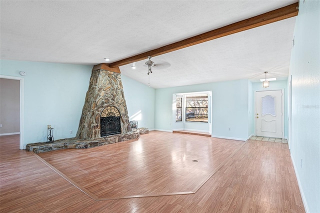 unfurnished living room featuring a textured ceiling, lofted ceiling with beams, a fireplace, and light hardwood / wood-style flooring