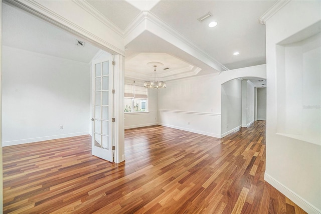 spare room featuring wood-type flooring, a notable chandelier, and ornamental molding