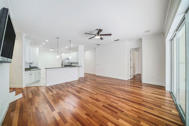 unfurnished living room featuring ceiling fan, light hardwood / wood-style floors, and crown molding