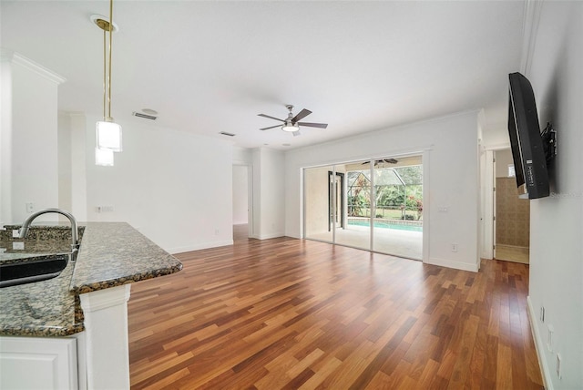 unfurnished living room featuring dark hardwood / wood-style flooring, ceiling fan, sink, and crown molding