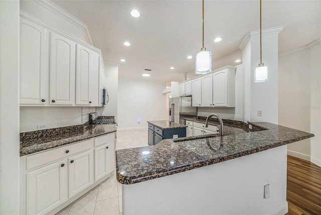 kitchen featuring white cabinetry, a center island, sink, decorative light fixtures, and appliances with stainless steel finishes