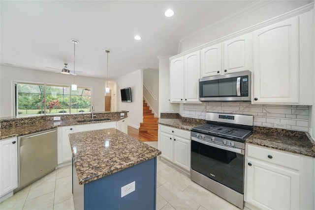 kitchen with appliances with stainless steel finishes, ceiling fan, sink, a center island, and hanging light fixtures