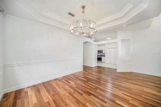 interior space with a notable chandelier, a raised ceiling, wood-type flooring, and ornamental molding