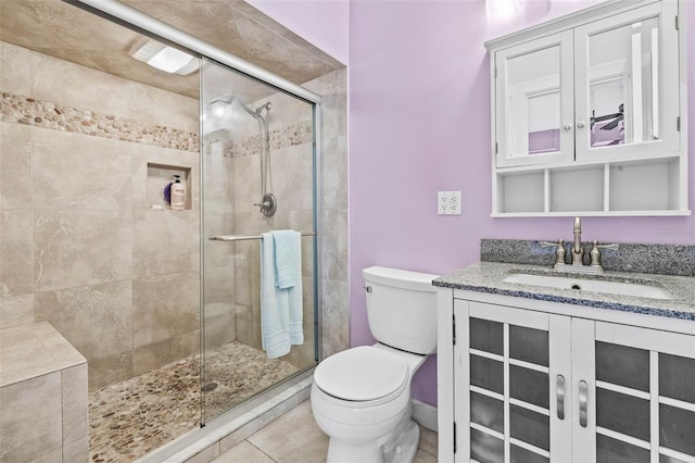 bathroom featuring tile patterned flooring, vanity, toilet, and a shower with shower door