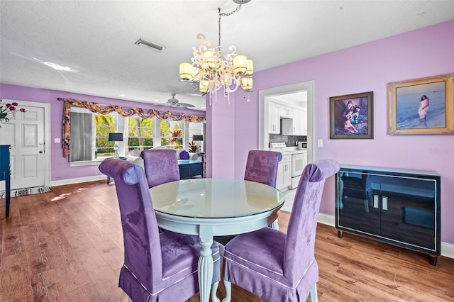 dining room with a textured ceiling, ceiling fan with notable chandelier, and light hardwood / wood-style floors