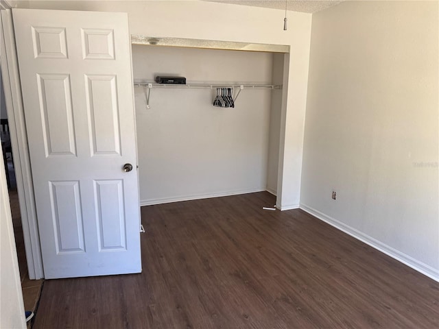 unfurnished bedroom featuring dark hardwood / wood-style flooring, a textured ceiling, and a closet