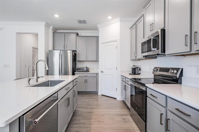 kitchen featuring gray cabinets, sink, ornamental molding, and stainless steel appliances