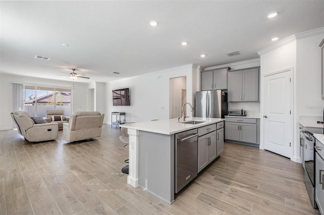 kitchen with appliances with stainless steel finishes, a center island with sink, gray cabinetry, and sink