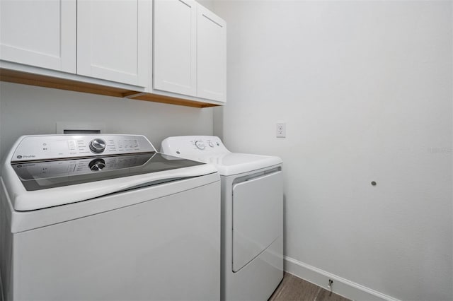 washroom with washer and dryer, dark hardwood / wood-style floors, and cabinets