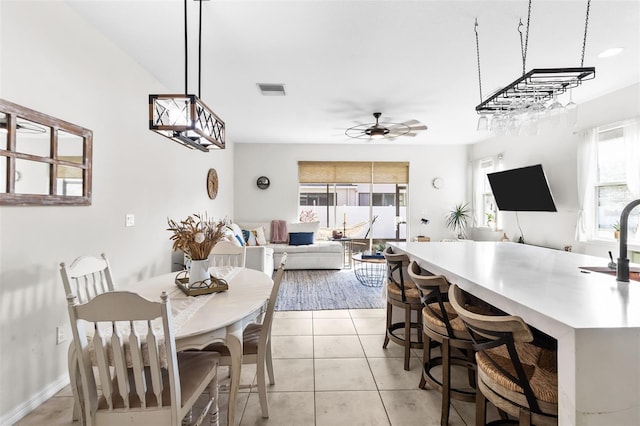 dining room featuring sink, ceiling fan with notable chandelier, and light tile patterned flooring